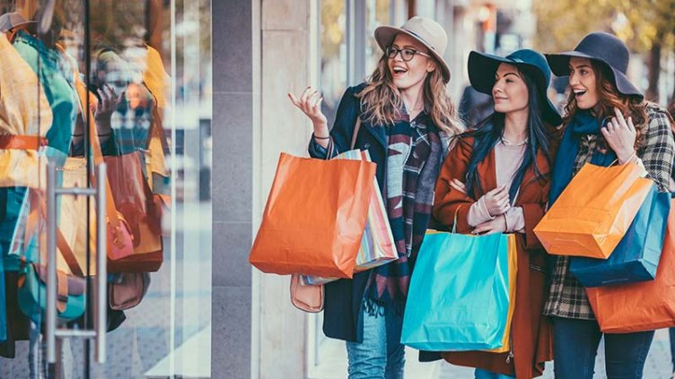 Friends are shopping clothes and holding bags
