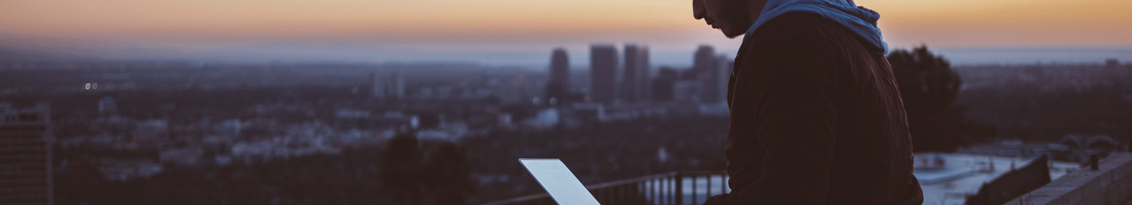 young man on rooftop using a laptop 