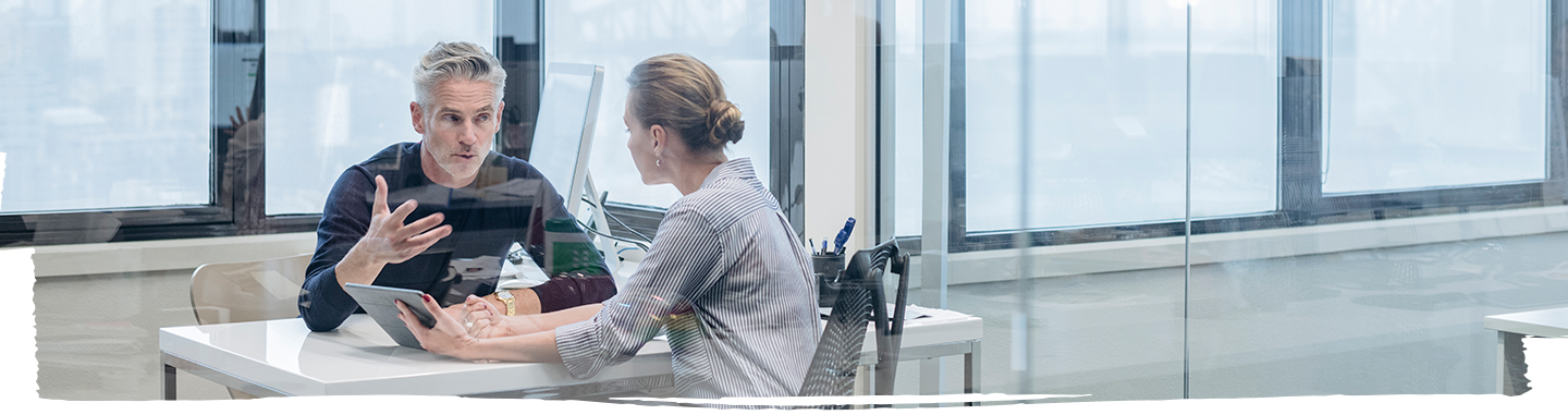 one male and female employee sitting in office cabing and discussing