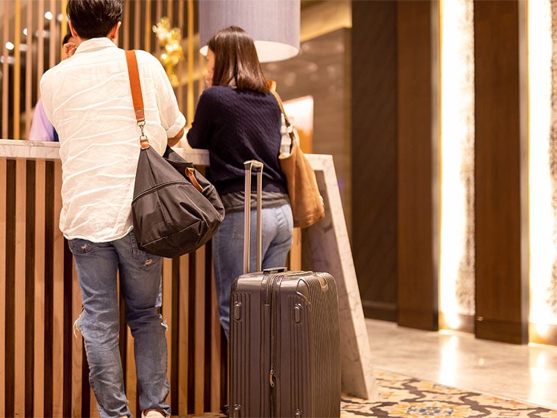 Asian couple with suitcase checking in at hotel reception