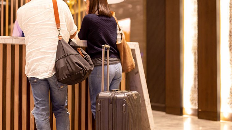 Asian couple with suitcase checking in at hotel reception