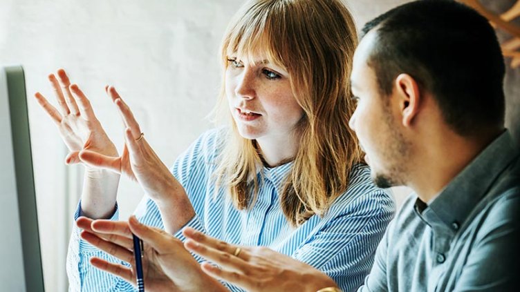 Two colleagues problem-solving at a computer together in the office